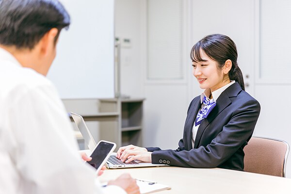 ショップの受付で携帯電話の契約手続きをする女性スタッフ