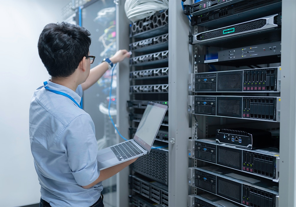 ノートパソコンを持ちながら、スーパーコンピューターの接続を確認する男性