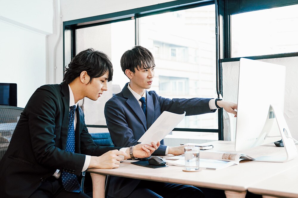 PCで設定を見直しているIT管理者とビジネスマン