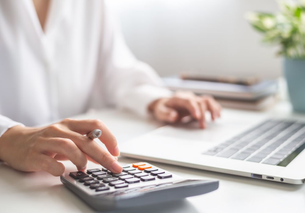 PCと電卓で計算を行っている女性
