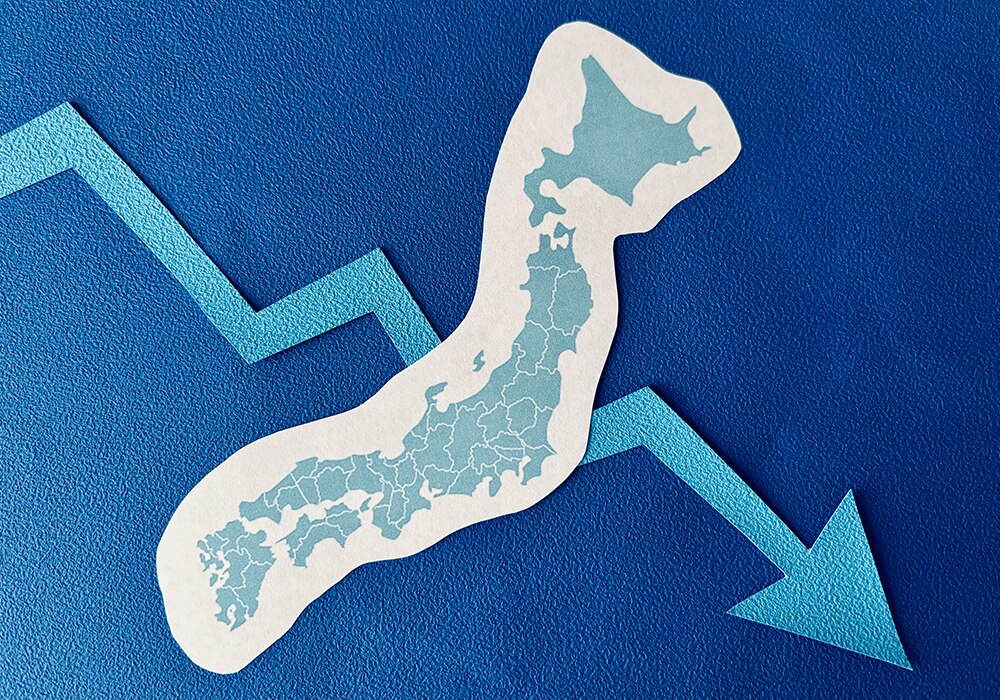 日本地図と経済指標の折れ線グラフが示す、経済の下降傾向のイメージ画像