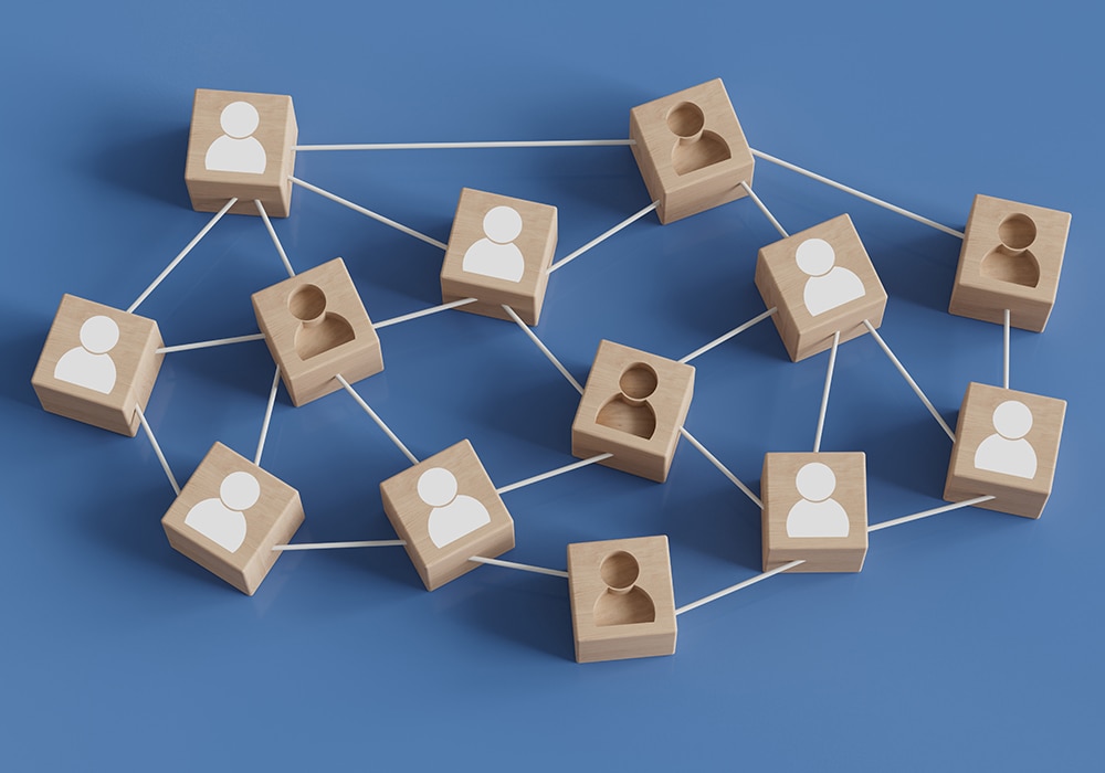 木製のブロックと線でつながれた人のアイコンが描かれたネットワーク図のイメージ画像