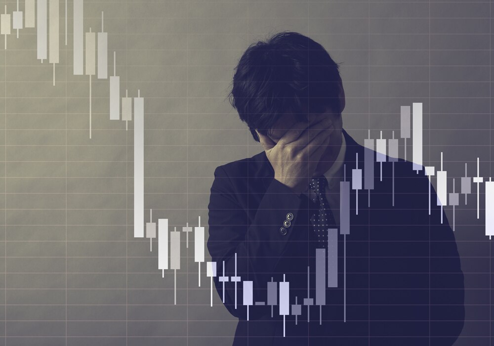 顔を手で覆い悲しんでいるビジネスマンのイメージ画像